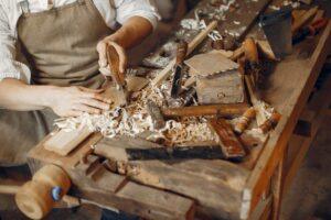 Ambachtsman aan een werkbank met handgereedschap en houtkrullen